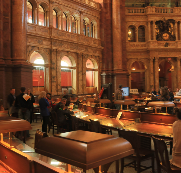 Interior room with desks and individuals reading materials at the Library of Congress in Washington, DC.