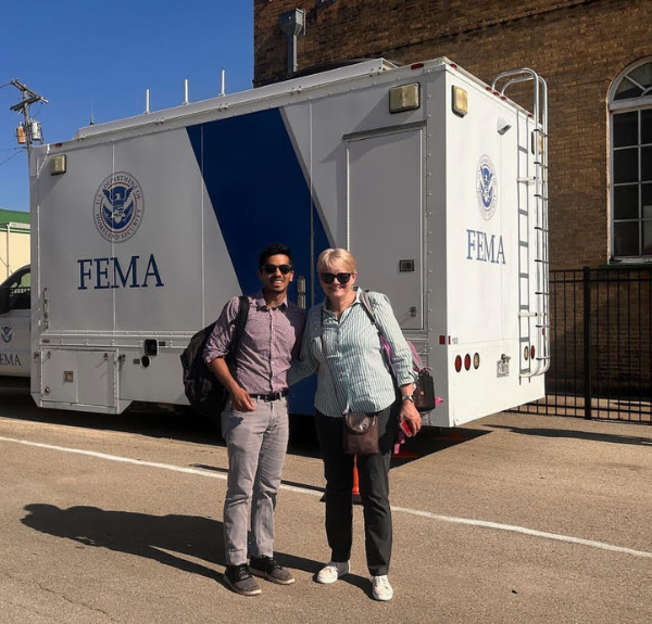 Two individuals standing on a road in front of FEMA truck.